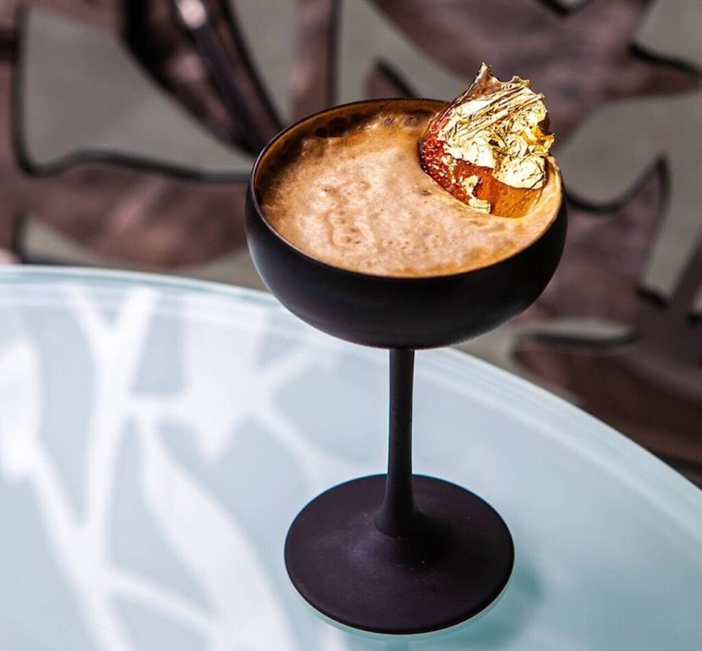 Drink served in dark cocktail glass resting on table for new brand expansion