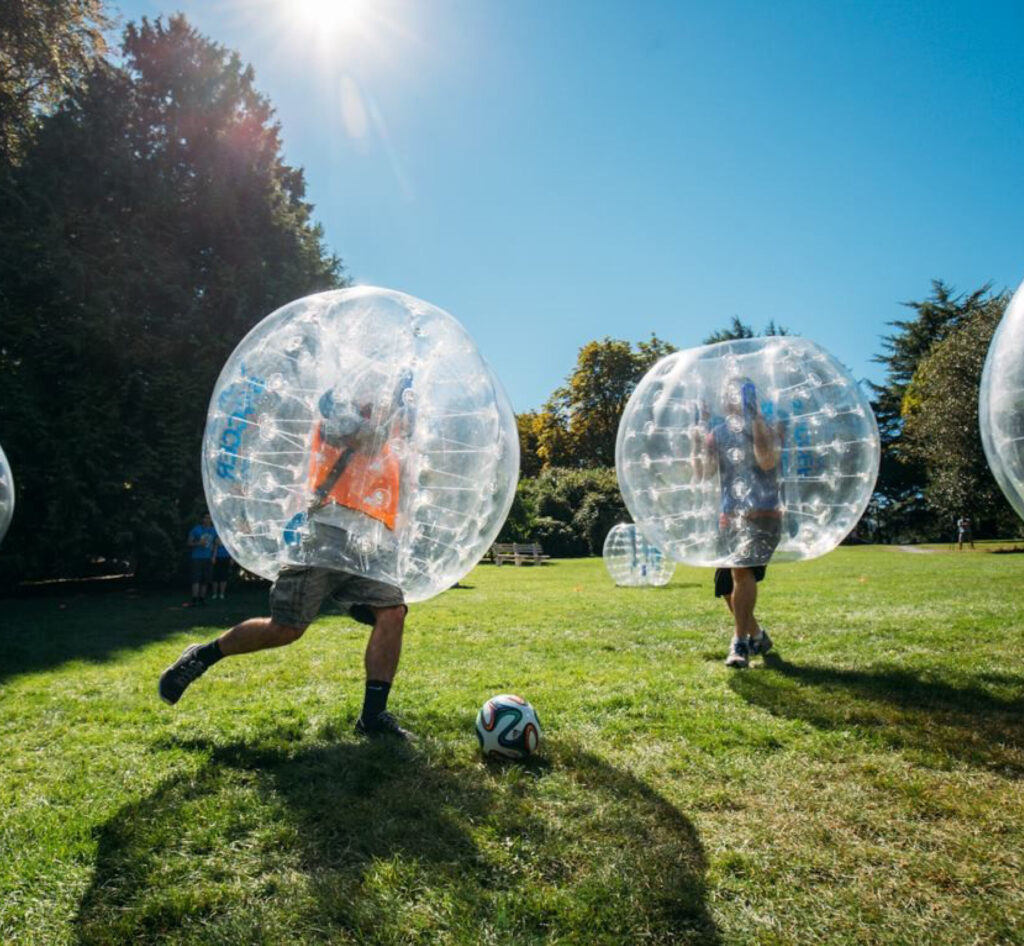 Two people playing soccer in inflatable bubbles